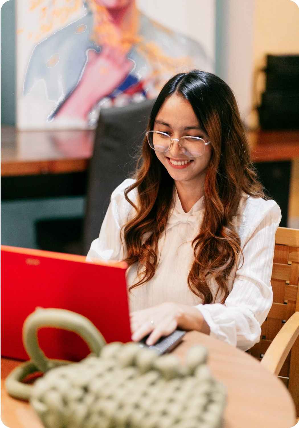 Offices for Rent in Makati (10) Woman with glasses typing on a red laptop in a cozy coworking lounge, showcasing a modern office for rent in Cebu.