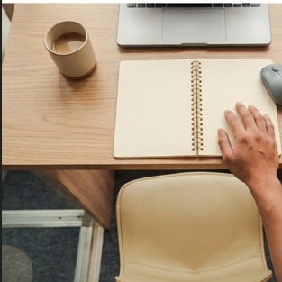 Notebook and laptop on a desk while a remote worker compares benefit details.